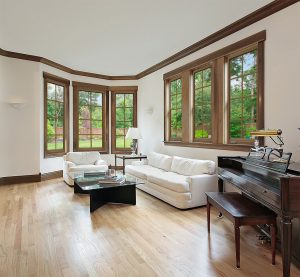 A living room with wood floors and wood-frame windows.