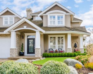 A large craftsman home with lush landscaping and lots of windows.