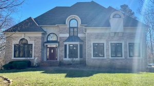 A house with dark roofing, stone siding, and lots of windows.