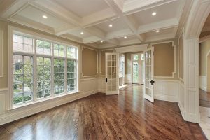 An empty living room with hardwood floors and a large window.