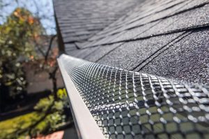Silver gutter guard running along residential roofing system.